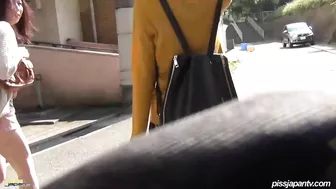 Japanese girl watches how girlfriend takes a piss on street