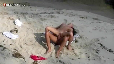Voyeur with camera films young couple having sex on beach