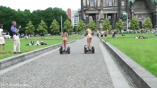 Red-haired and brunette girls walk around city totally naked