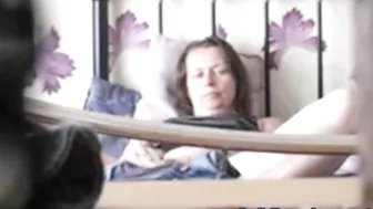 Black-haired mature caught masturbating on the bed being alone at home