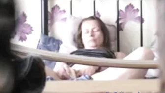 Black-haired mature caught masturbating on the bed being alone at home