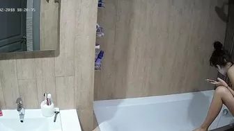 A tall woman talks on the phone before hopping in the tub in this caught sister