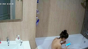 A tall woman talks on the phone before hopping in the tub in this caught sister
