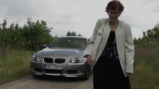 Rich dude stops his expensive car to pick up old red-haired granny with glasses for outdoor blowjob