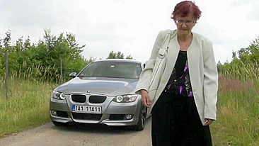 Rich dude stops his expensive car to pick up old red-haired granny with glasses for outdoor blowjob
