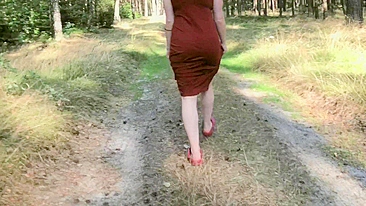 Redhead teases by flashing big boobs while peeing in forest.