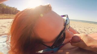 Sexy redhead gives public beach blowjob with sunglasses on.