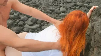 Red-haired woman standing on beach having sex and cream pie, risqué.