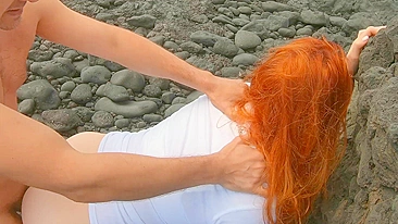 Red-haired woman standing on beach having sex and cream pie, risqué.