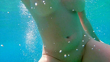 Redhead teen swims nude underwater while receiving a hand job from her gorgeous partner.