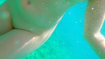 Redhead teen swims nude underwater while receiving a hand job from her gorgeous partner.